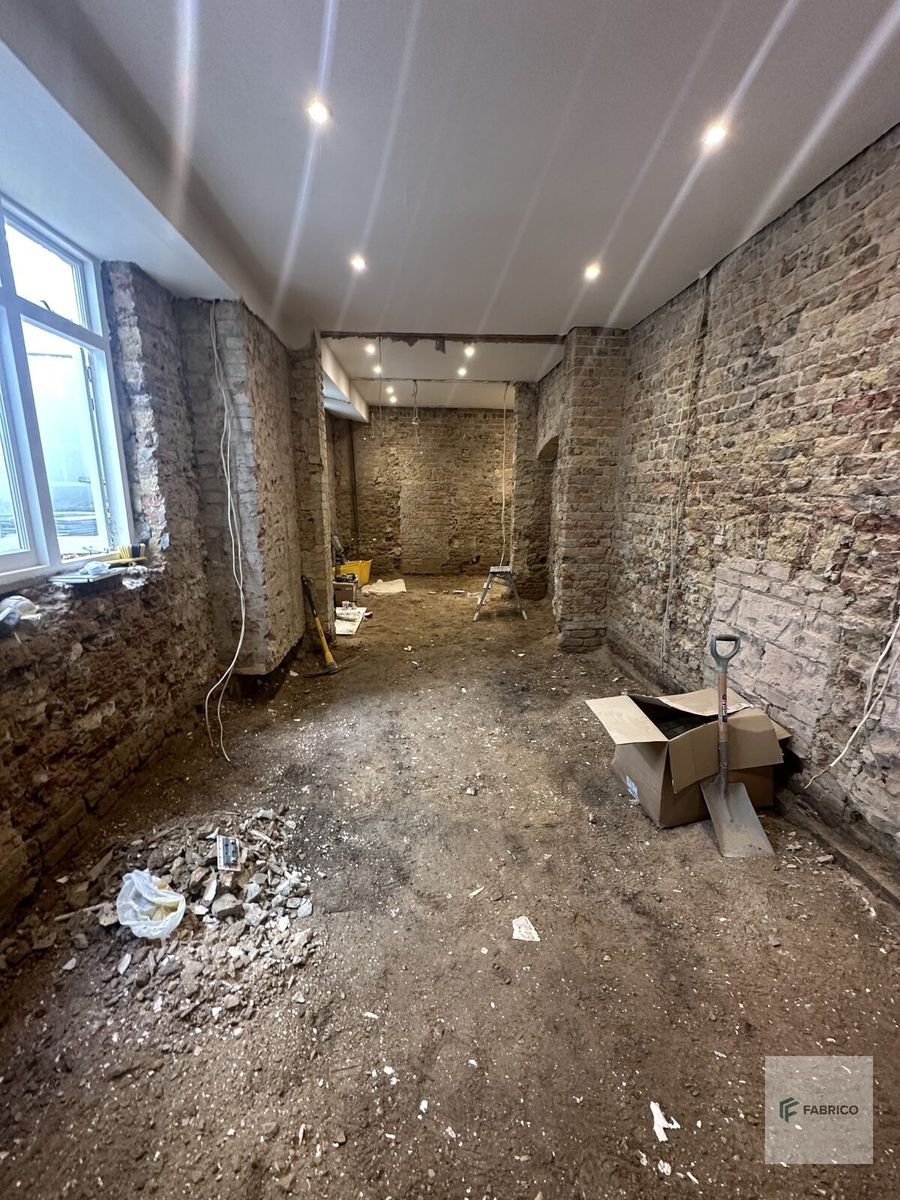 Basement strip-out — exposed brick walls and recessed lighting
