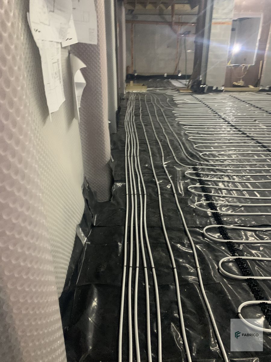 Corridor view of underfloor heating pipes laid with cavity membrane and first-fix services